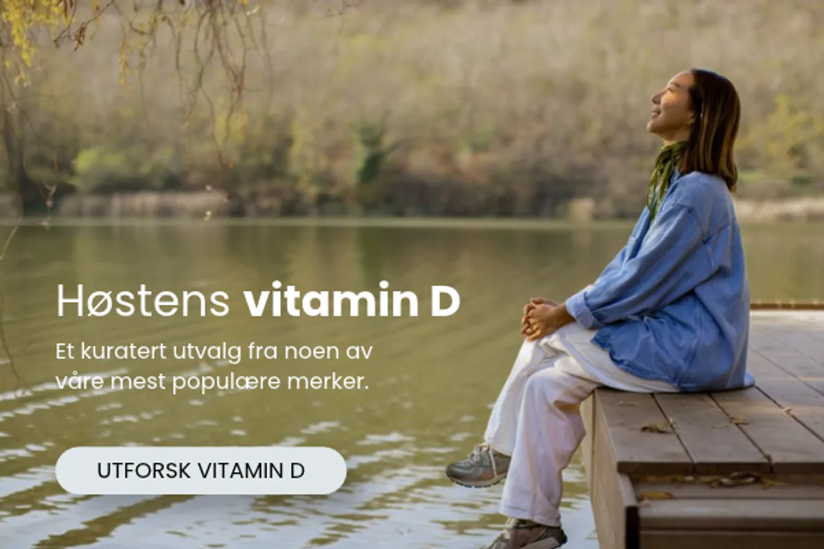 Kvinne sitter ved vannet i høstlandskap med tekst om høstens vitamin D hos vitaminX.
